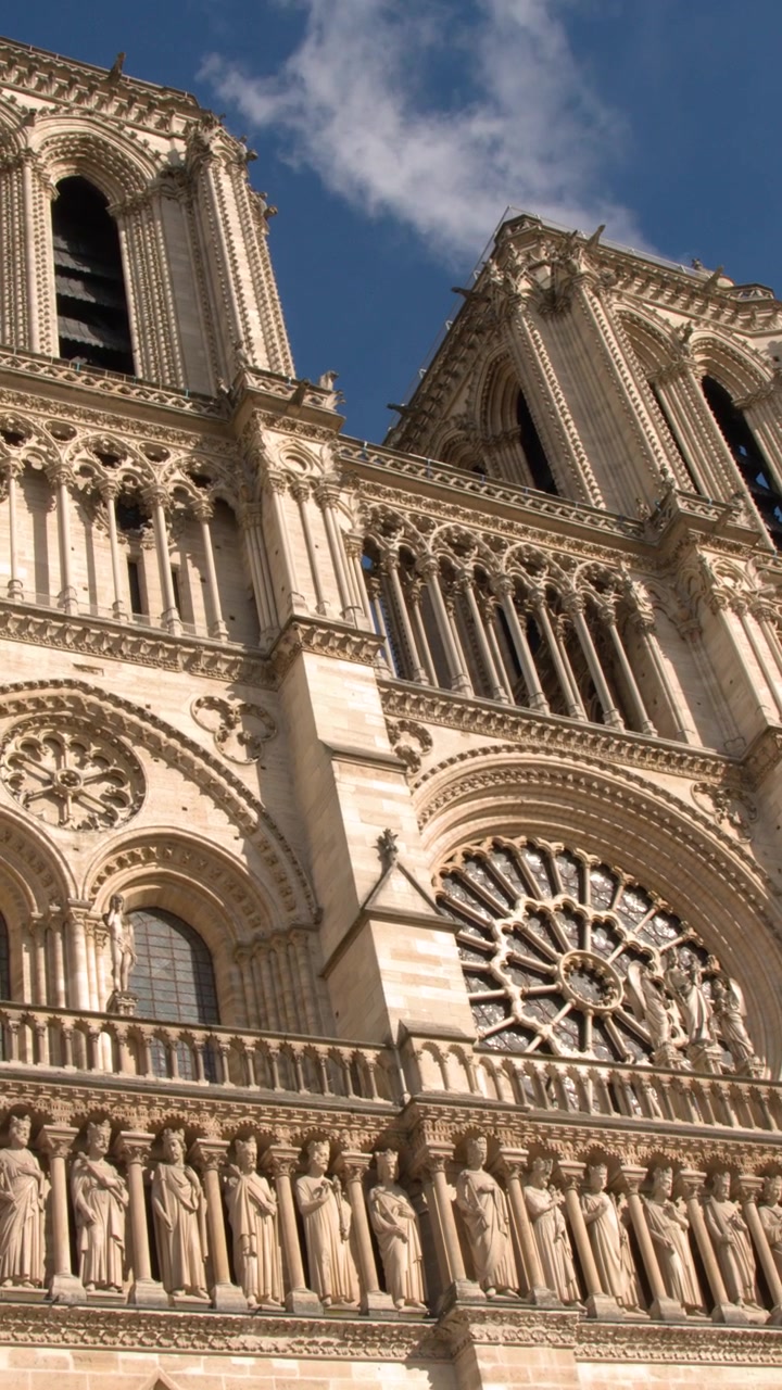 Inquadratura dal basso verso l'alto che mostra l'intricata architettura gotica e le sculture in pietra della Cattedrale di Notre Dame.