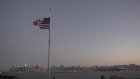 Slow-Motion-of-American-National-Flag-Waving-on-Pole-With-San-Francisco-Skyline-in-Background,-California-USA