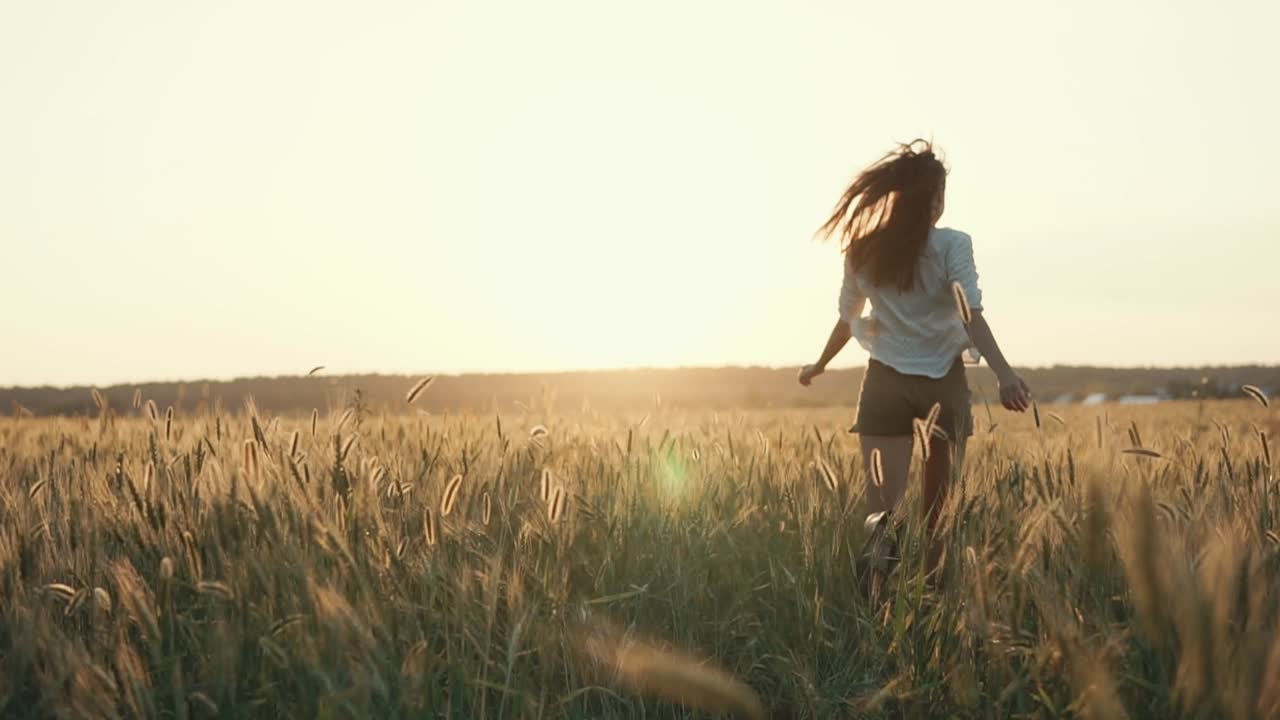 mujer corriendo por un campo de trigo al atardecer