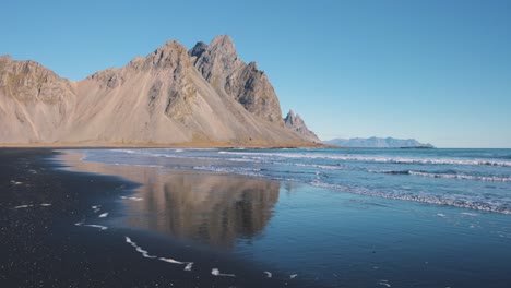 Pico-Vestrahorn-Que-Se-Eleva-Sobre-La-Playa-De-Arena-Negra-Bañada-Por-Las-Olas-Del-Mar.