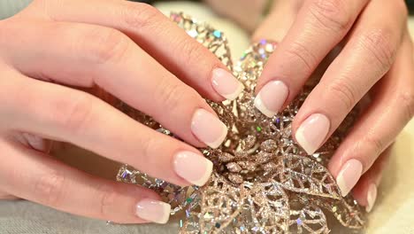 french manicure finger nails holding a sparkling holiday ornament