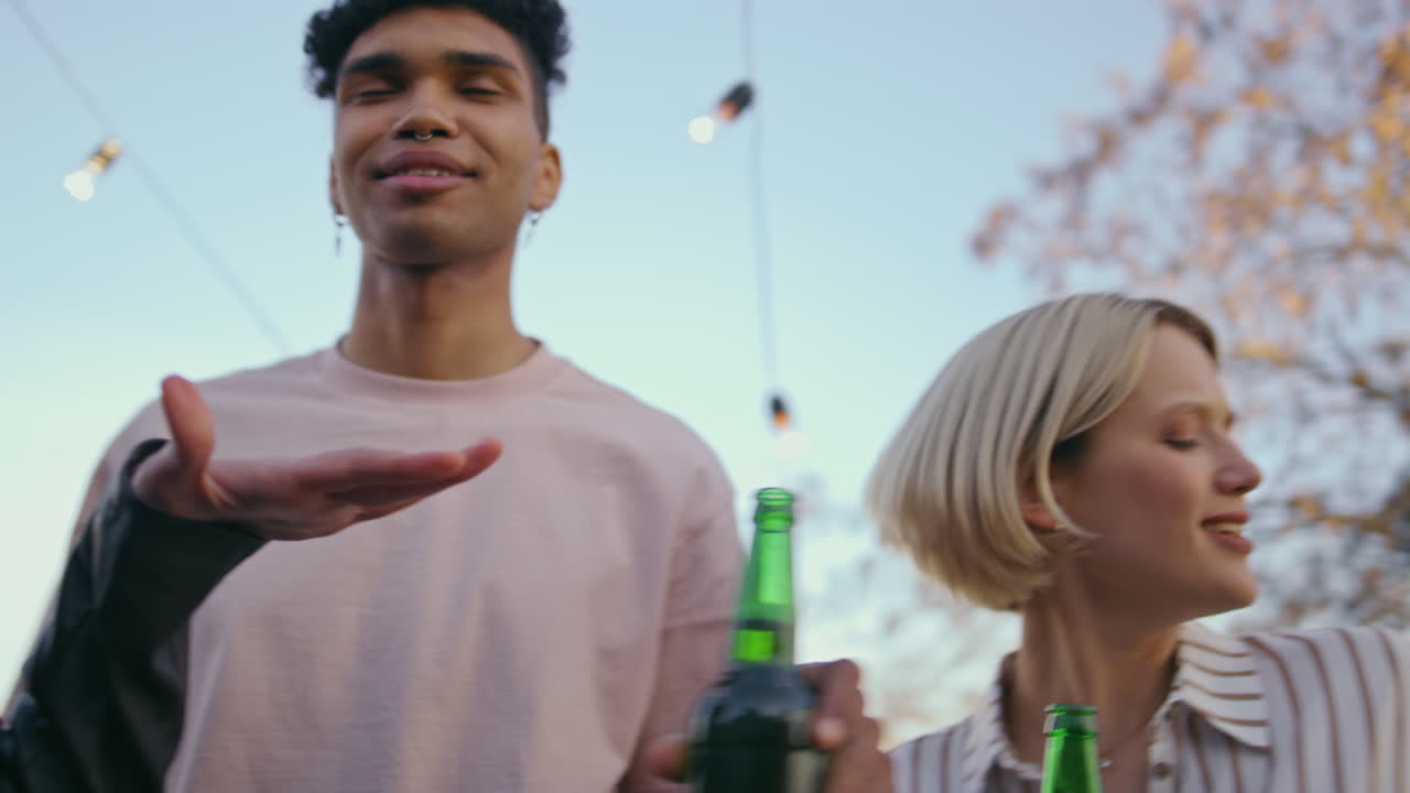 Dansende pige til tagfest, nærbillede. Glade venner nyder øl og lytter til musik.