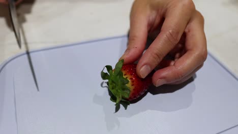 a strawberry being sliced on a cutting board