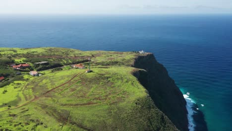 aerial of green cliffs above blue atlantic water with ponta do pargo lighthouse