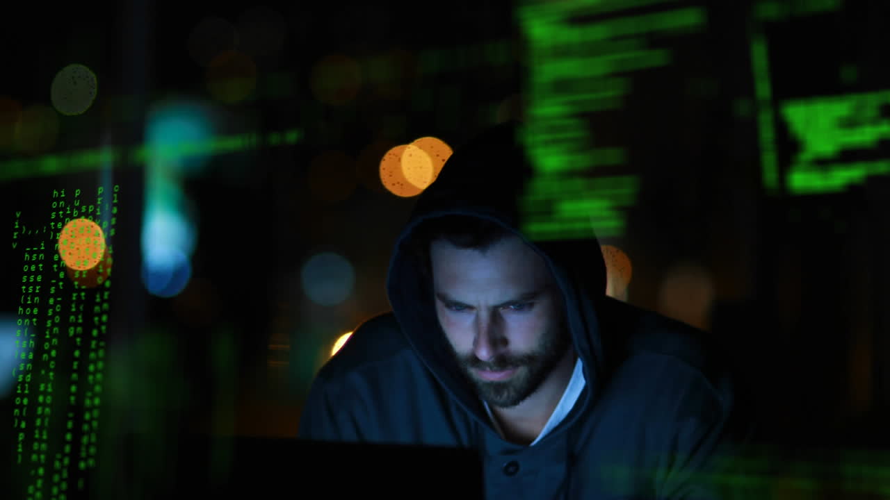 Hacker in a dark room working on a laptop