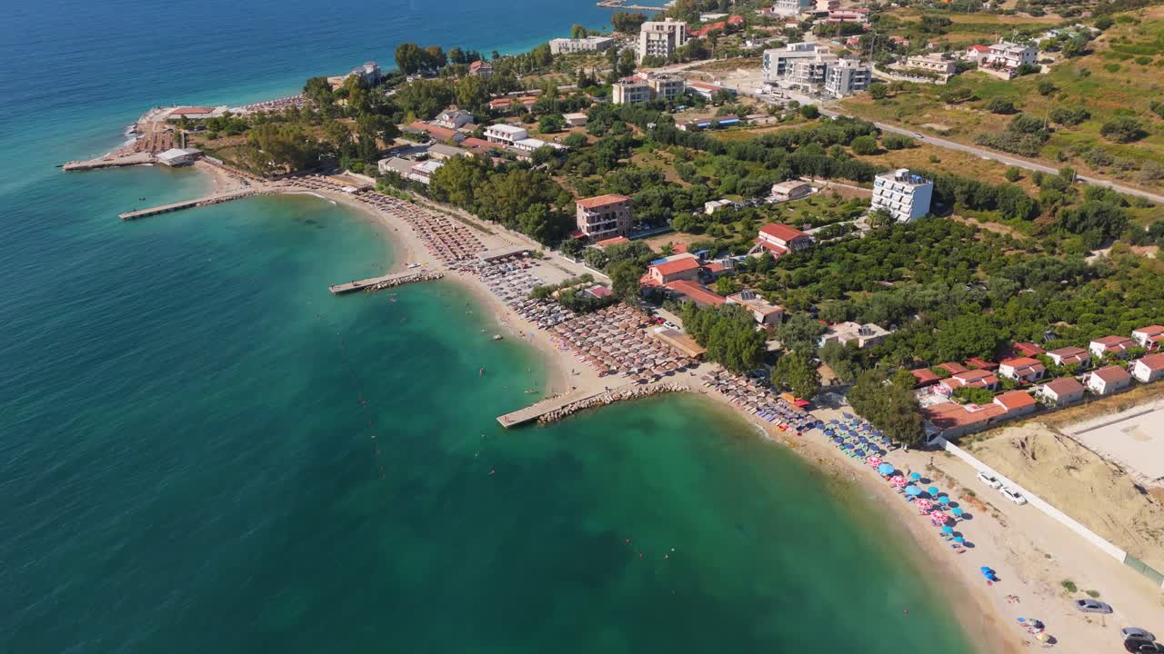 vista aérea de una hermosa playa con aguas claras de color turquesa y filas de paraguas en albania