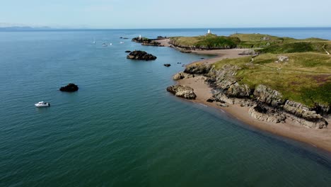 yates que navegan frente a ynys llanddwyn, la costa de la isla de marea galesa, vista aérea en órbita de la exuberante costa