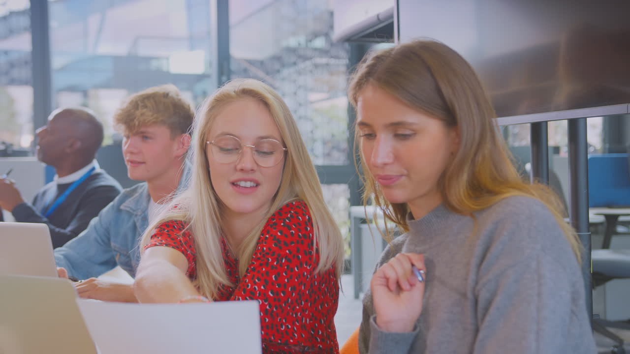 대학이나 대학생들이 튜터와 함께 테이블 주위에 앉아 노트북에서 세미나에 협력하고 있습니다.