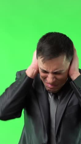 businessman reacting to unbearable noise on green screen