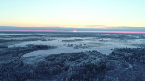 Vista-Panorámica-Desde-Arriba-Que-Muestra-Bosques-Nevados-Con-Puesta-De-Sol-Púrpura-En-El-Horizonte---Vista-Aérea