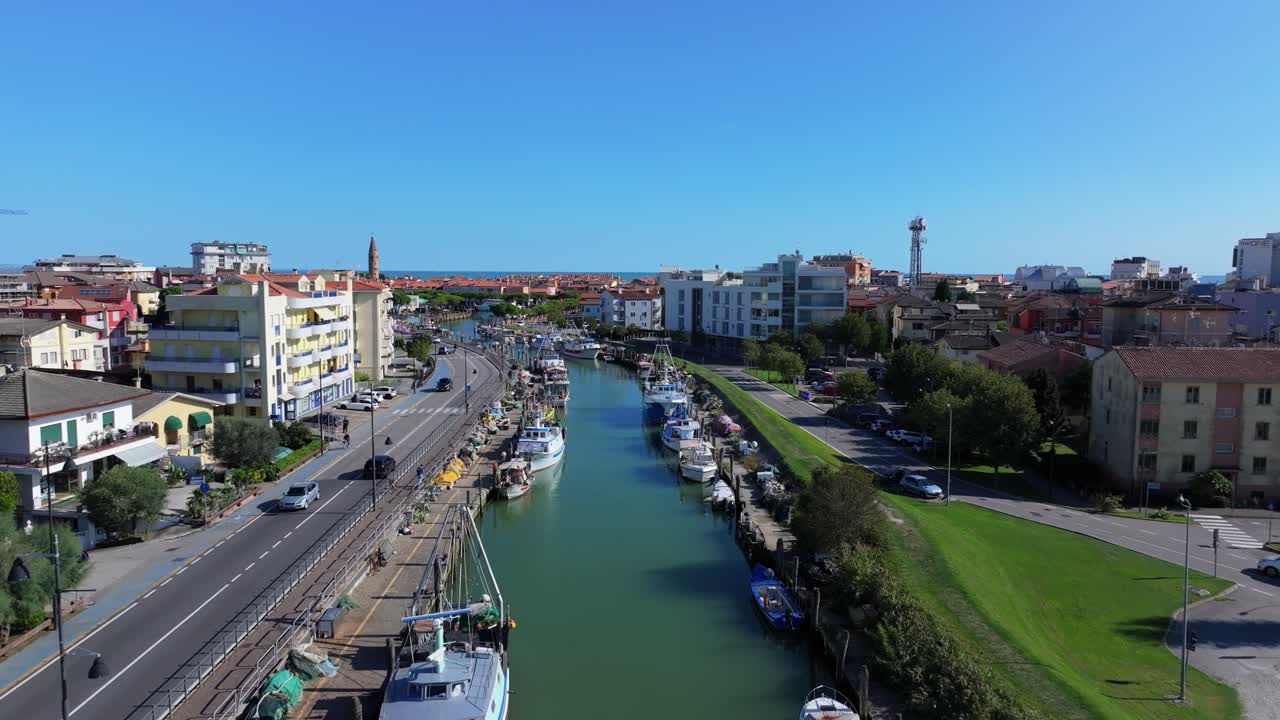 low-flying aerial of the commercial canal in Caorle, Italy, slowly rising to reveal the Adriatic Sea