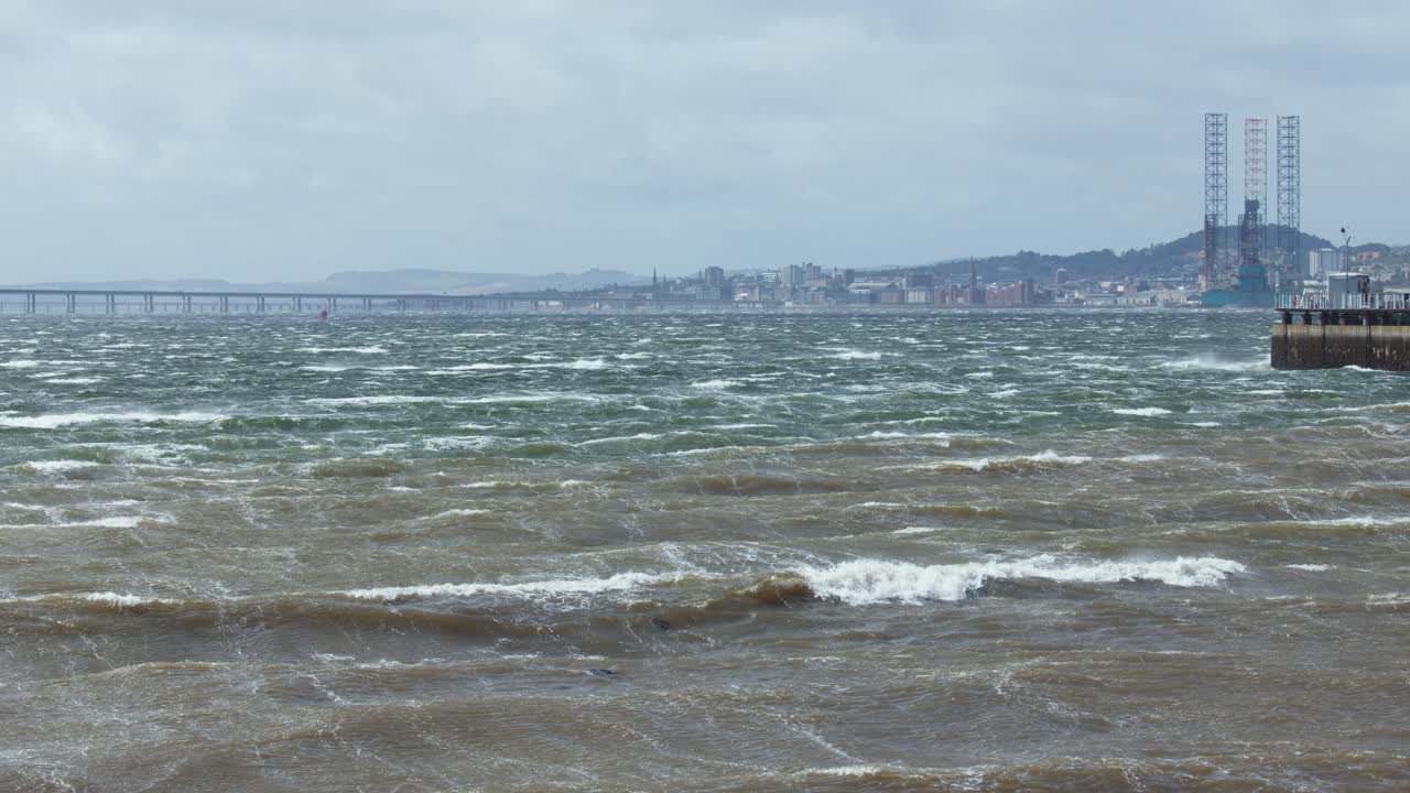 Windy day with choppy sea, waves, pier, distant hills, and overcast sky at Broughty Ferry