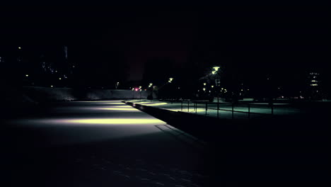 pan shot of frozen pond covered with snow in a city park with traffic in background