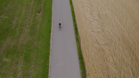 wide shot of cyclist race in country road next to farm fields