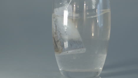 tea bag being moved in glass of hot water in slow motion