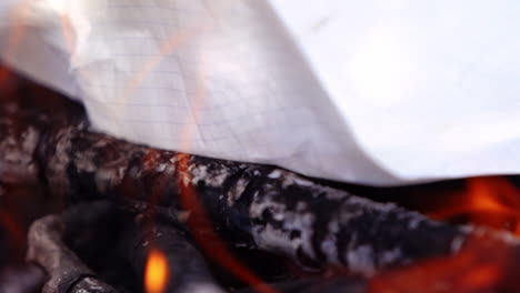 paper and logs are burning in an outdoor fire. flames all around. campsite fire video.