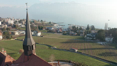 Flying-past-church-tower-overlooking-green-field