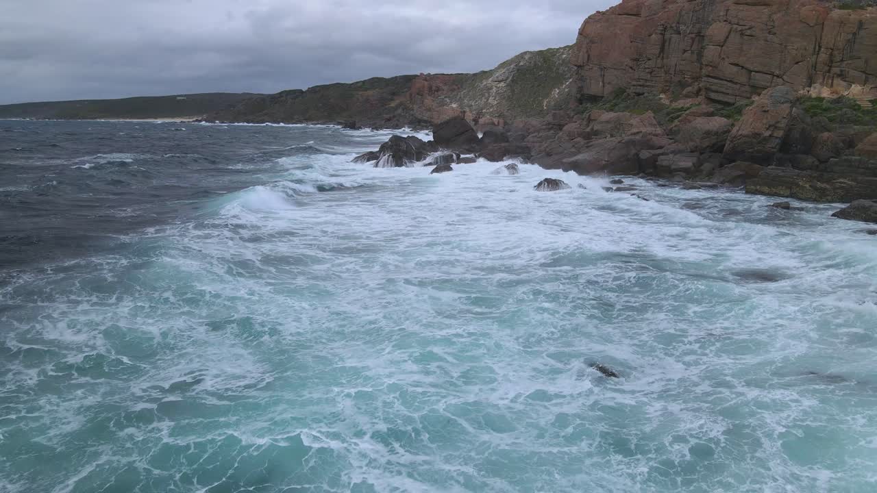 sobrevuelo fuertes olas rompiendo rocas durante la tormenta en un día nublado en la playa australiana