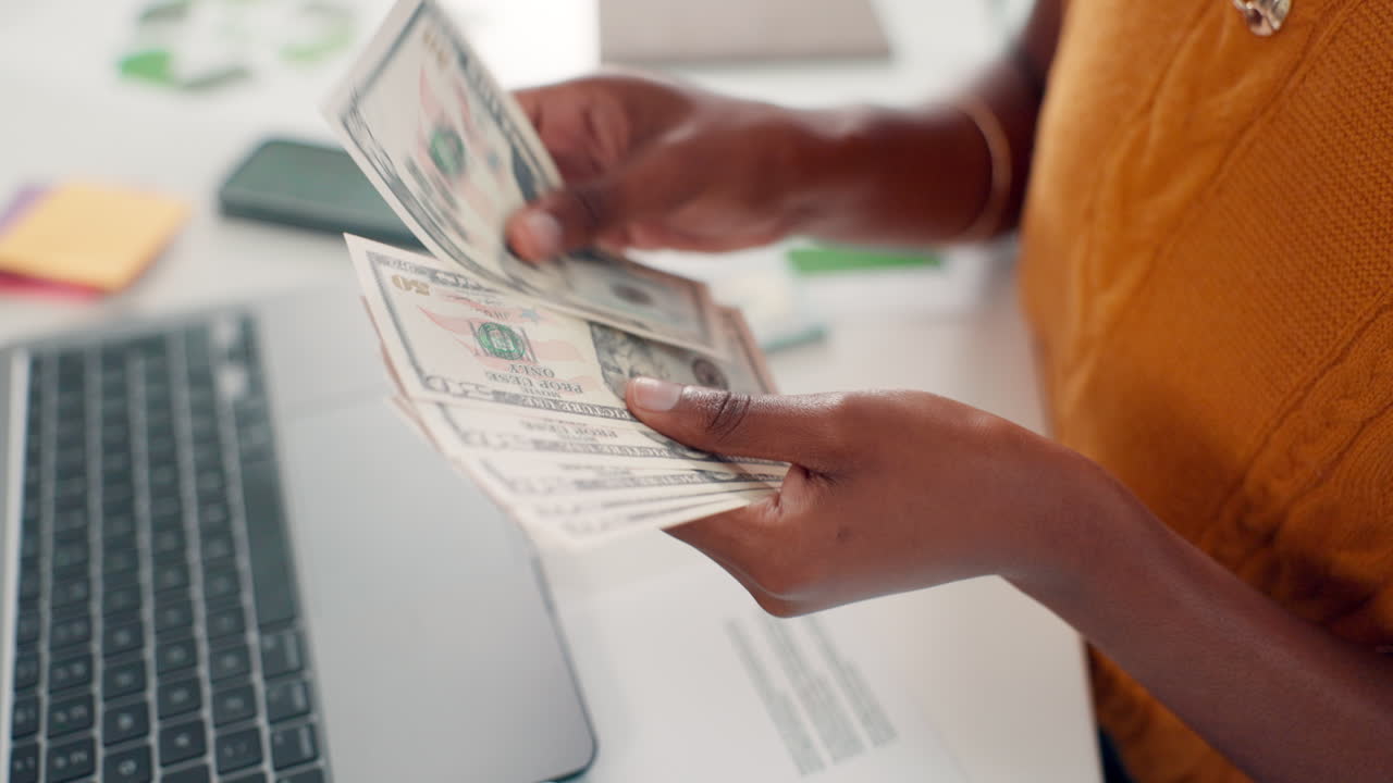 Close Up of Hands Counting Fifty Dollar Bills on a Desk