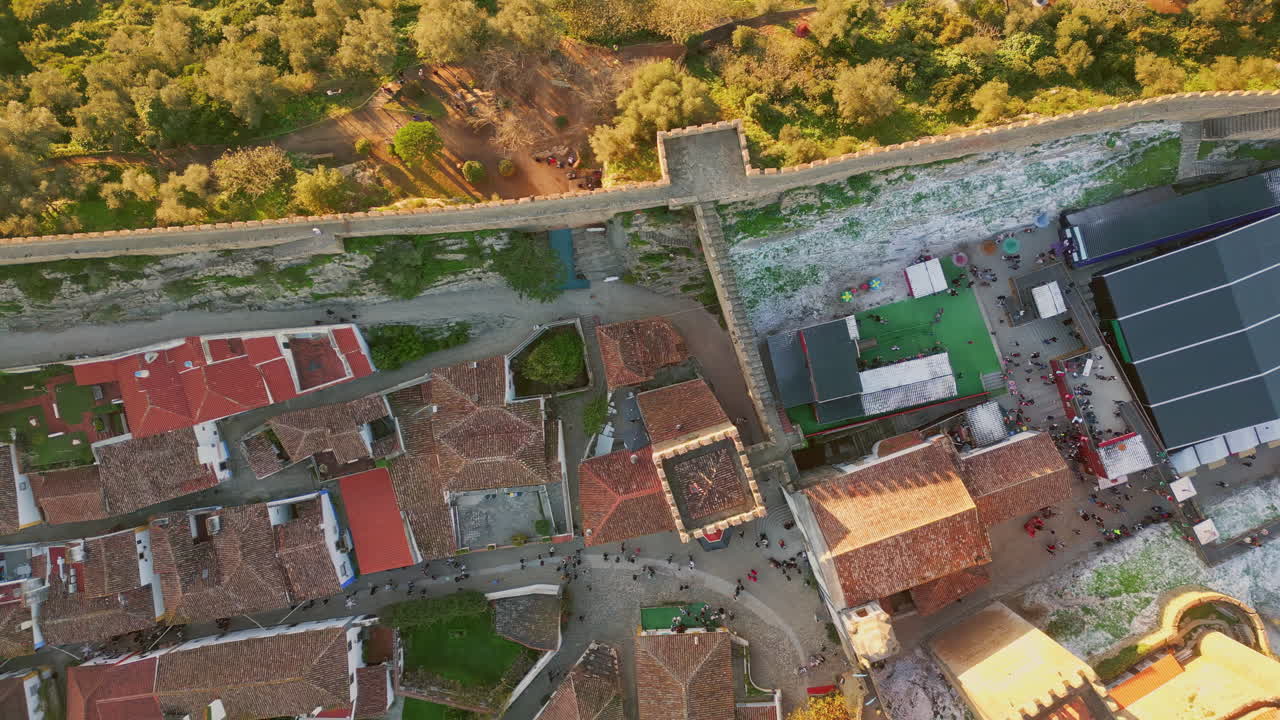 Aerial view village rooftops with red tiles sunny evening. Castle stone wall