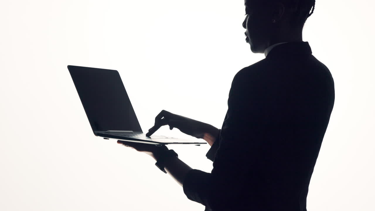 Silhouette of a person using a laptop