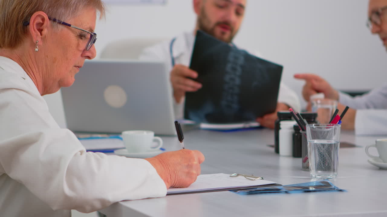 un primer plano de una mujer anciana tomando notas en el clipboard.