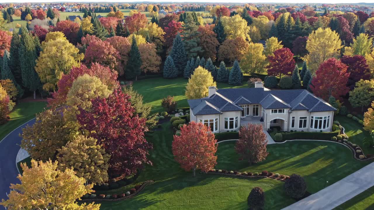 Aerial view of a luxurious estate surrounded by vibrant autumn foliage, showcasing an elegant