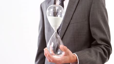 Businessman-holding-sandglass-against-white-background