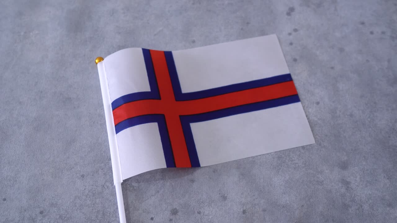 Færøyenes flagg i nærbilde på grå bakgrunn. Færøysk nasjonalflagg.