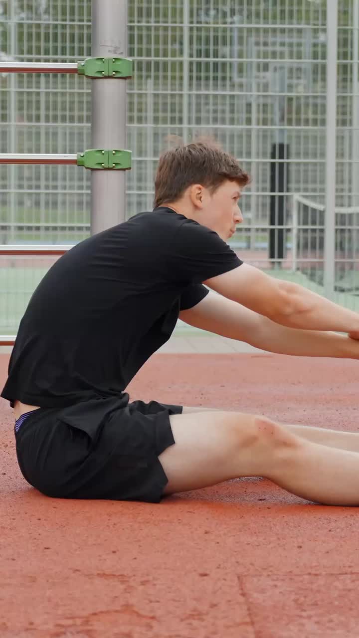 Uomo caucasico che fa stretching alle gambe prima di allenarsi in un campo all'aperto. - scatto verticale