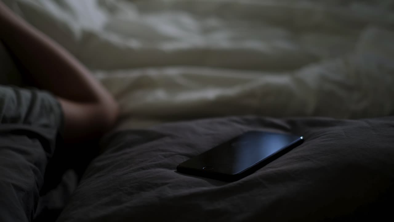 전화 를 들고 침대 에 누워 있는 사람