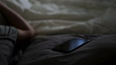 person lying in bed with phone