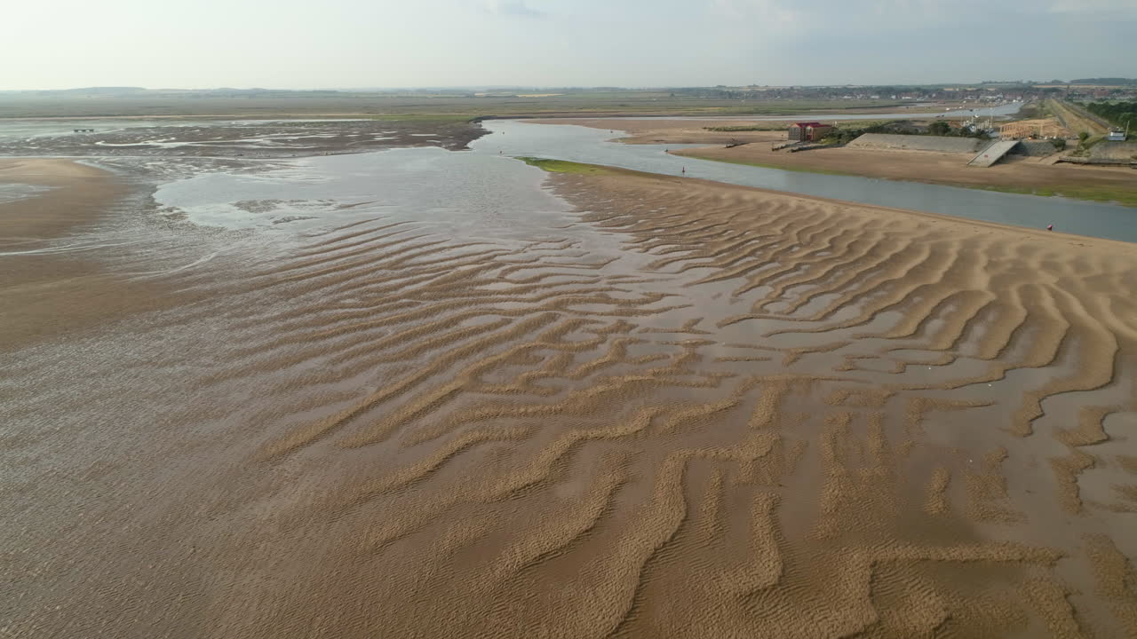 drone de establecimiento bajo disparó sobre ondas de arena durante la marea baja en wells-next-the-sea creek con la antigua casa de botes salvavidas north norfolk, reino unido, costa este