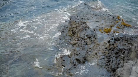 suaves olas en cámara lenta que se lavan a través de las rocas costeras concepto relajante repetición calmante