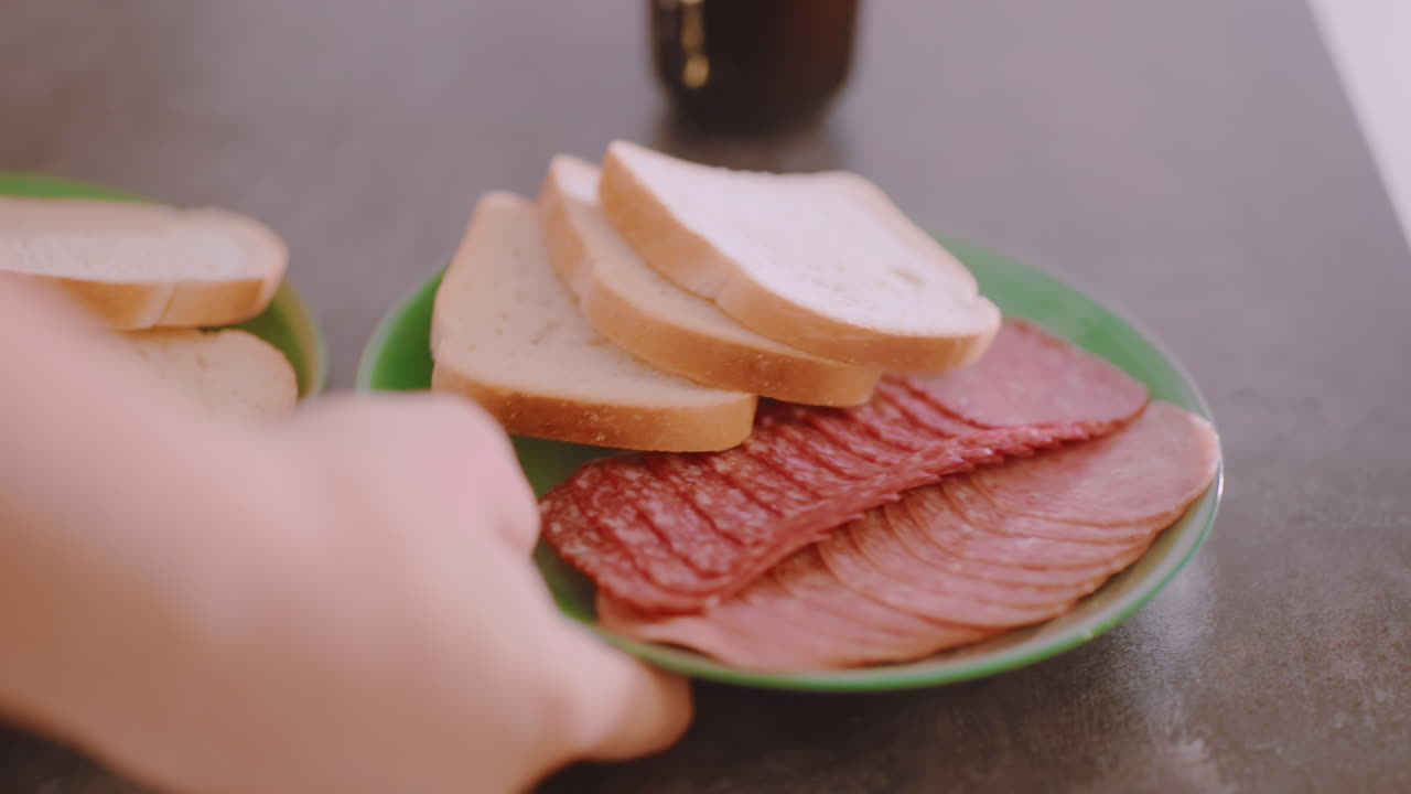 Close up of sliced bread and meat on green plate taken from table surface with blurred hot coffee cup in background, creating cozy breakfast scene with detail on fresh food