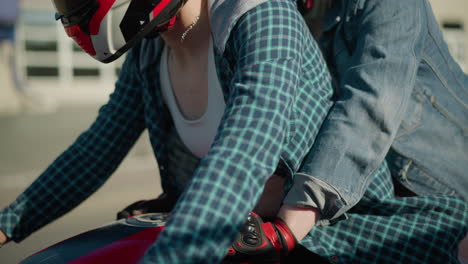 two ladies ride through an urban road on a power bike, passing buildings and a parked car, the rider's necklace moves with the motion of the bike, the background is slightly blurred