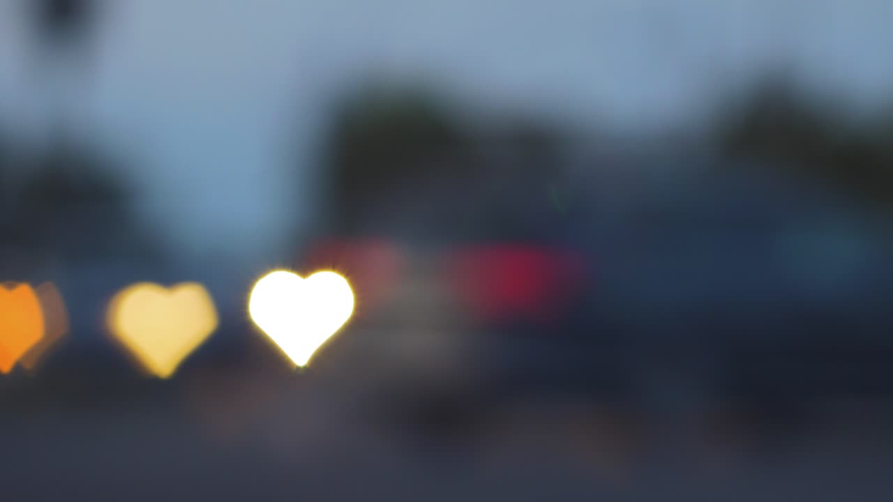 저녁, 발렌타인 데이, 결혼식 날 또는 배경 개념과 같은 소셜 미디어에서 움직이는 자동차와 신호등에서 아름다운 하트 보케