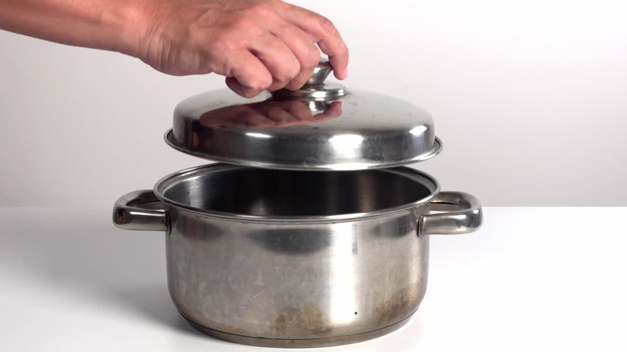 Hand Placing Lid on Stainless Steel Cooking Pot