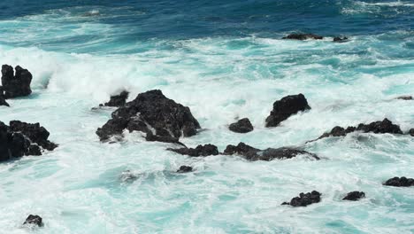 wave creates white foam as it crashes on volcanic rocks of tenerife