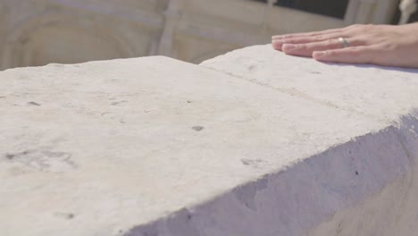 woman's hand resting on a stone wall of a historic building