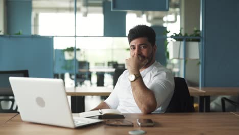 Porträt-Eines-Gutaussehenden,-Stilvollen-Jungen-Mannes-Arabischer-Herkunft,-Der-Mit-Einem-Laptop-In-Einem-Modernen-Businesscenter-Büro-Sitzt