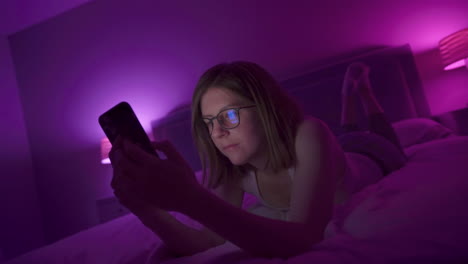girl browses social media on smart phone late at night in bedroom.