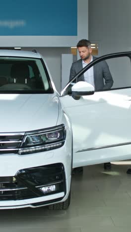 customer looking at a white suv in a car showroom