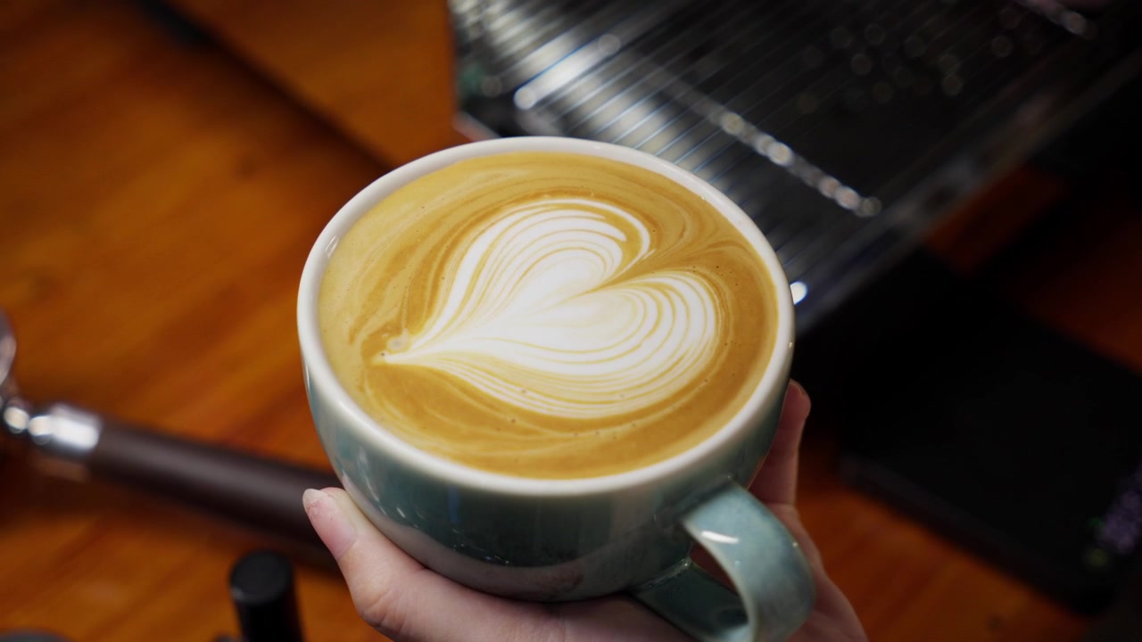 Un barista professionista crea intricate latte art, la macro inquadratura evidenzia la schiuma di latte setosa e la colata di espresso scuro per un caffè perfetto