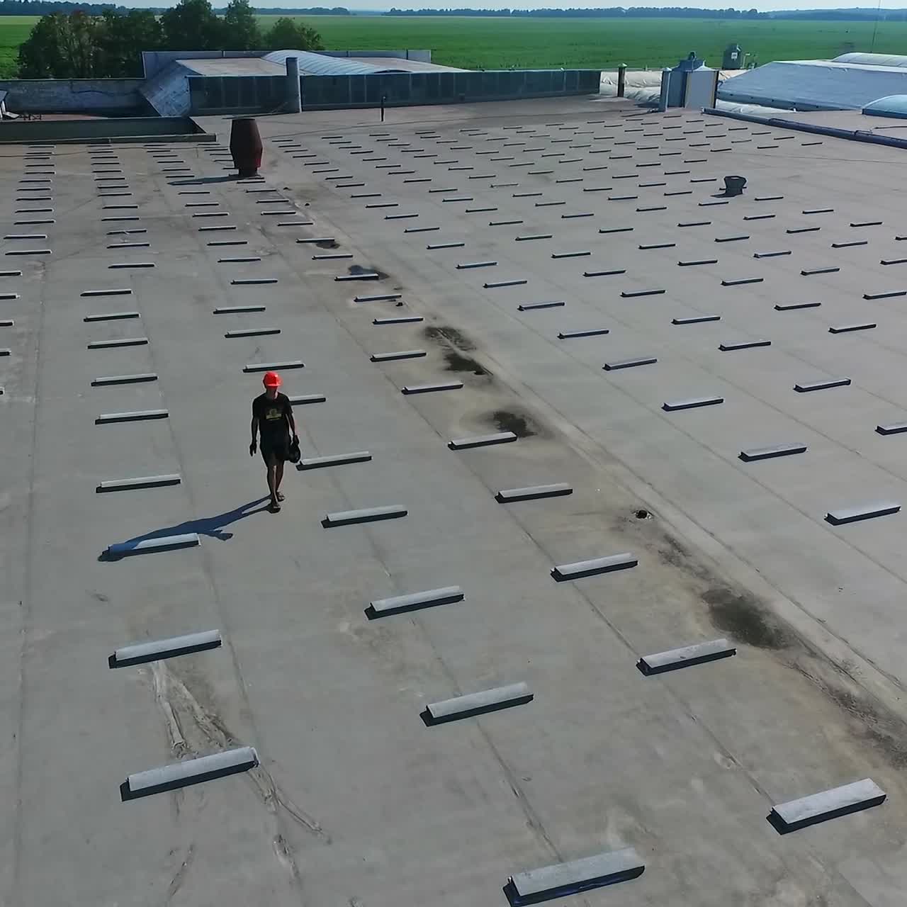 Building the solar farm on flat roof. Flying over the construction site of future alternative power plant on the top of building. Aerial view.