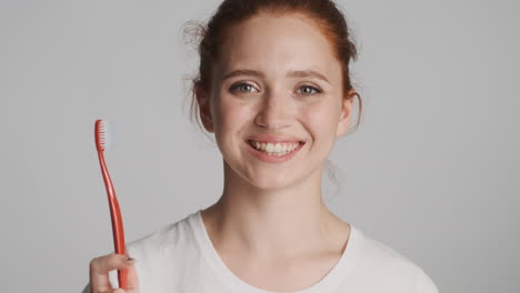 redheaded girl in front of camera on gray background.