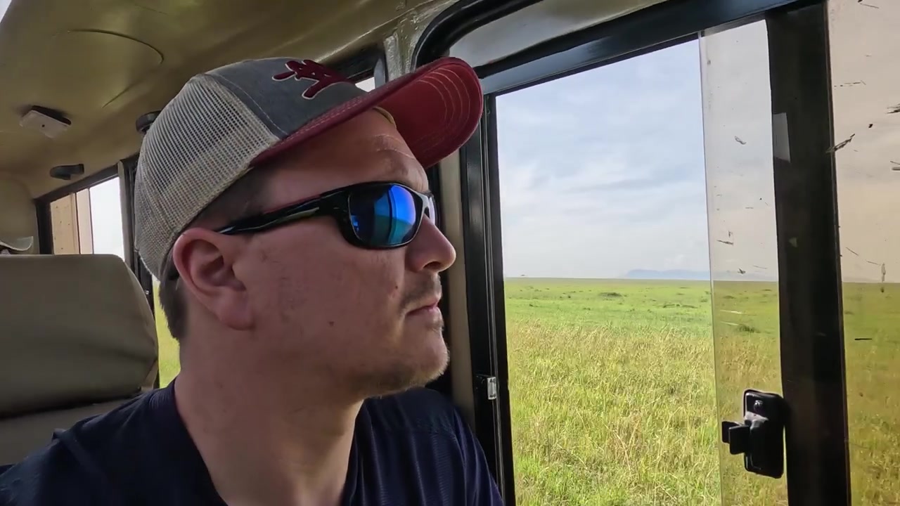 Tourist with cap watching wildlife from inside a safari vehicle window view