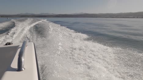 pov rear and side wake from powerboat motoring offshore on sunny day