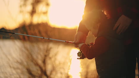 father-is-teaching-his-little-son-to-catch-fish-by-fishing-rod-dad-and-child-are-spending-time-together