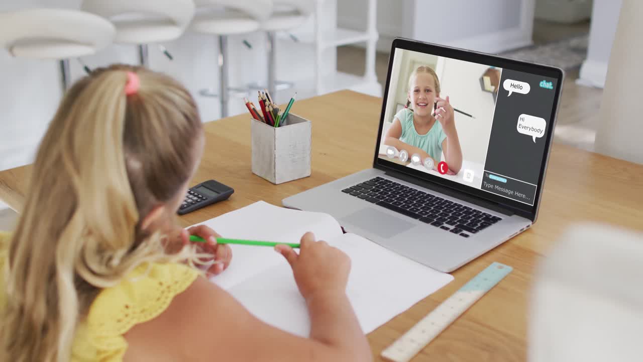 Schoolgirl using laptop for online lesson at home, with girl talking and web chat on screen